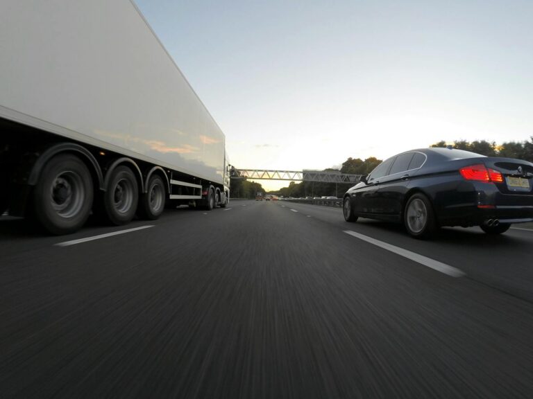Cars and a truck speed along a highway under the clear sky, showcasing transportation dynamics.